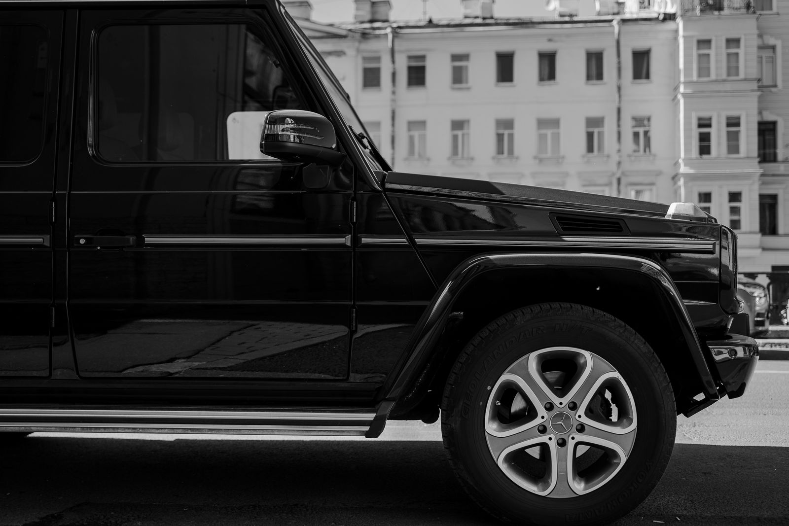 Side view of a Mercedes SUV in black and white on a city street, showcasing luxury and style.